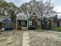 Charming green home featuring a cozy front porch, flowering trees, and a brick chimney at 2505 Chapel Hill Rd, Durham, NC 27707