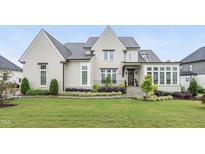 Beautiful two-story home with a manicured lawn and lush landscaping in a suburban neighborhood at 329 Broad Elm Ln, Apex, NC 27523