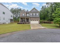 Charming two-story home with a well-manicured lawn and a two-car garage and welcoming front porch at 352 Fire Opal Ln, Holly Springs, NC 27540