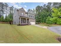 Beautiful two-story home featuring a manicured lawn, two car garage, and a charming covered front porch at 352 Fire Opal Ln, Holly Springs, NC 27540