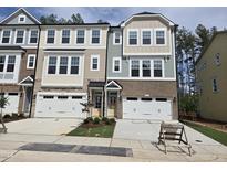 Charming townhome exterior features brick accents, white garage doors and manicured landscaping at 5028 Jowetts Walk Dr # 24, Cary, NC 27519