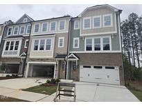 Modern townhome boasts an attached garage, complemented by large windows and brick and siding details at 5028 Jowetts Walk Dr # 24, Cary, NC 27519