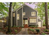 Charming two-story home with gray siding, white trim, and a welcoming front porch surrounded by mature trees at 6035 Sentinel Dr, Raleigh, NC 27609