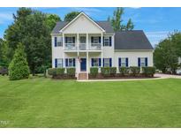 Charming two-story home with a beautifully maintained lawn, American flag, and welcoming front porch at 750 Raymond Dr, Clayton, NC 27527