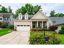 Charming home featuring a two-car garage, front porch, and well-manicured landscaping at 1577 Tice Hurst Ln, Apex, NC 27502