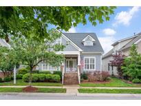 Charming two-story home with a landscaped front yard, brick stairs, and an American flag at 1633 Lakestone Village Ln, Fuquay Varina, NC 27526