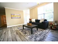 Inviting living room featuring a comfortable dark sofa, stylish rug, and light, airy ambiance at 1912 Parkside Village Dr, Clayton, NC 27520