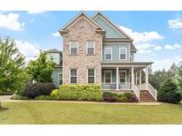 Charming two-story home with a brick and blue exterior, front porch, and well-manicured landscaping at 212 Preatonwood Dr, Apex, NC 27539