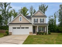 Charming two-story home with a well-manicured lawn, attached garage, and inviting front porch at 2521 Heathland Farm Dr, Fuquay Varina, NC 27526