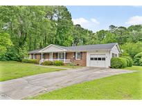 Charming brick ranch home with well-manicured lawn, covered porch, and attached garage on a tree-lined street at 3114 Alabama Ave, Durham, NC 27705