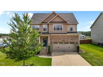 Beautiful two-story home with brick and vinyl siding, attached two-car garage, and well-manicured lawn at 319 Brinkley Cir, Mebane, NC 27302