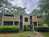 Exterior view of a tan two-story townhome with brick facade on the lower level at 3559 Mill Run, Raleigh, NC 27612