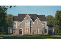 Charming two-story home featuring stone accents, arched entryway, and lush green lawn at 441 Lila Dr, Pittsboro, NC 27312