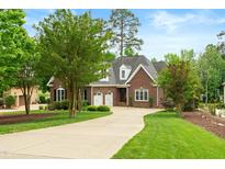 Charming brick home featuring a well-manicured lawn and a long, curved driveway leading to a two-car garage at 498 Mountain Laurel, Chapel Hill, NC 27517