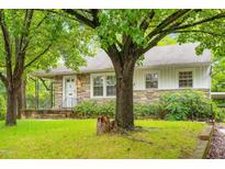 Charming single-story home with stone accents, a covered porch, and mature trees shading the front yard at 504 Delaware Ave, Burlington, NC 27217