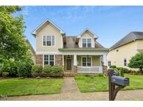 Charming home with a stone and shake exterior, a cozy front porch, and a well-manicured lawn at 59 Tobacco Farm Way, Chapel Hill, NC 27516