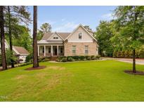 Charming two-story brick home boasts a manicured lawn and a welcoming front porch at 623 Cabin Crk, Pittsboro, NC 27312