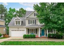 Charming two-story home with a manicured front lawn, attached garage, dormer windows and a welcoming blue front door at 1004 Manderston Ln, Apex, NC 27502