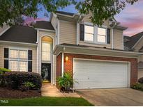 Charming home with a two-car garage, brick accents, and manicured landscaping under a colorful twilight sky at 103 Lake Tillery Dr, Cary, NC 27519