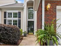 Inviting front entrance with a black door, transom window, brick accents, and lush landscaping at 103 Lake Tillery Dr, Cary, NC 27519