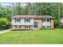 Charming split-level home featuring a brick facade, well-manicured lawn, and mature trees at 1109 Buckingham Rd, Garner, NC 27529