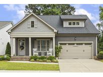 Charming home with a covered front porch, two rocking chairs, and attractive landscaping at 1374 Patriot Points Way, Fuquay Varina, NC 27526