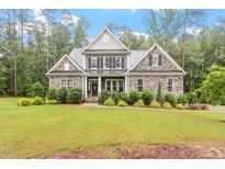 Charming two-story home featuring a stone facade, gray shingles, and lush landscaping at 1508 Banks Brooke Dr, Raleigh, NC 27603