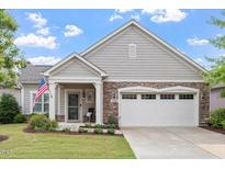 Charming home featuring stone accents, a covered porch, manicured lawn, and an attached two-car garage at 228 Ellisview Dr, Cary, NC 27519