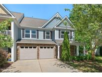 Two-story townhome featuring stone accents, gray siding, and a two-car garage, set against a blue sky at 3002 Bartlett Cir, Hillsborough, NC 27278