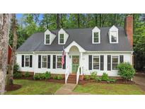 Charming home featuring a green door with a wreath, black shutters and well manicured landscaping at 3016 Bolo Trl, Raleigh, NC 27615