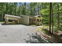 Charming home with a covered carport and welcoming red front door nestled in a lush, wooded setting at 305 Old School Rd, Chapel Hill, NC 27516