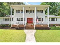 Charming two-story home featuring a white exterior, front porch, red door and well-maintained lawn at 307 Country Club Dr, Durham, NC 27712