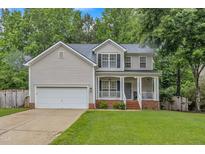 Charming two-story home with a well-maintained lawn, attached garage, and inviting front porch with classic columns at 4028 Winecott Dr, Apex, NC 27502