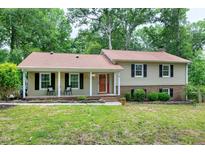 Traditional two-story home with a welcoming front porch, black shutters and a red front door surrounded by a lush lawn at 5121 Raintree Rd, Durham, NC 27712