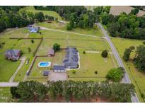 Expansive aerial view of a large country home with a pool, barn, and surrounding green pastures at 5200 Pulley Town Rd, Zebulon, NC 27597