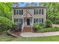 Charming two-story home with wood siding, black shutters, manicured lawn, and an American flag at 5805 Bayberry Ln, Raleigh, NC 27612