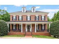 Beautiful brick home featuring dormer windows, black shutters, and a welcoming covered front porch at 6217 Battleford Dr, Raleigh, NC 27612