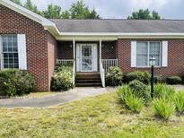Welcoming brick home featuring a white railed porch and mature landscaping at 65 Opie Frazier Rd, Henderson, NC 27537