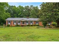 Charming brick home with well-maintained lawn, blue shutters, and a welcoming front porch at 6909 Hickory Dr, Raleigh, NC 27603