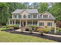Inviting two-story home with a charming front porch and manicured landscaping at 7811 Still Crossing Rd, Chapel Hill, NC 27516