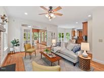 Bright living room featuring hardwood floors, neutral walls, sunroom access, and open layout to the kitchen at 7811 Still Crossing Rd, Chapel Hill, NC 27516
