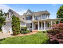Charming two-story home with a welcoming front porch, landscaped yard, and attached two-car garage at 100 Maywood Way, Chapel Hill, NC 27516