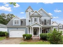 Charming blue two-story home with lush front yard and attached garage, providing curb appeal at 1217 Heritage Greens Dr, Wake Forest, NC 27587