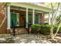 Inviting brick home featuring a charming covered front porch with blue door and matching shutters at 126 Solterra Way, Durham, NC 27705