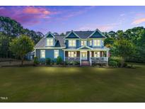 Stunning two-story blue house with a welcoming front porch and beautifully manicured lawn at 227 Paraggi Ct, Clayton, NC 27527