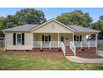 Charming home with a cozy front porch, white railings, and brick accents at 304 S Smith St, Clayton, NC 27520