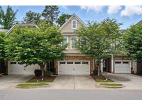 Charming townhome featuring a two-car garage, stone accents, and lush landscaping at 369 Roberts Ridge Dr, Cary, NC 27513