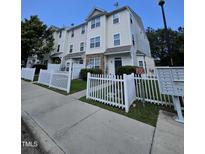 A cream-colored townhouse complex featuring a white picket fence and well-maintained landscaping at 401 Coalinga Ln # 106, Raleigh, NC 27610