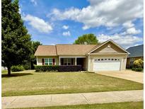 Inviting one-story home featuring a well-manicured lawn and a charming front porch at 411 Joneshaven Dr, Fuquay Varina, NC 27526