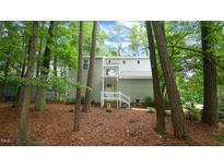 Two-story home with light siding and a welcoming porch nestled among mature trees and natural foliage at 516 Ryan Rd, Cary, NC 27511